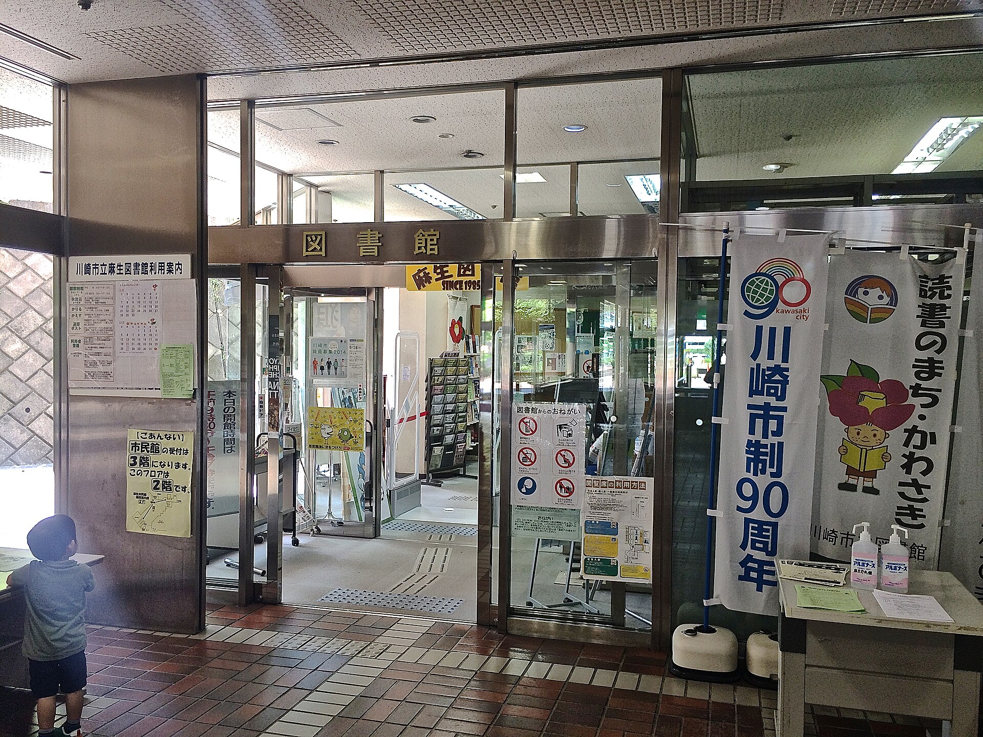 麻生図書館の入口。「図書館」の文字の上に、黄色い看板の「麻生図 SINCE 1985」が見える