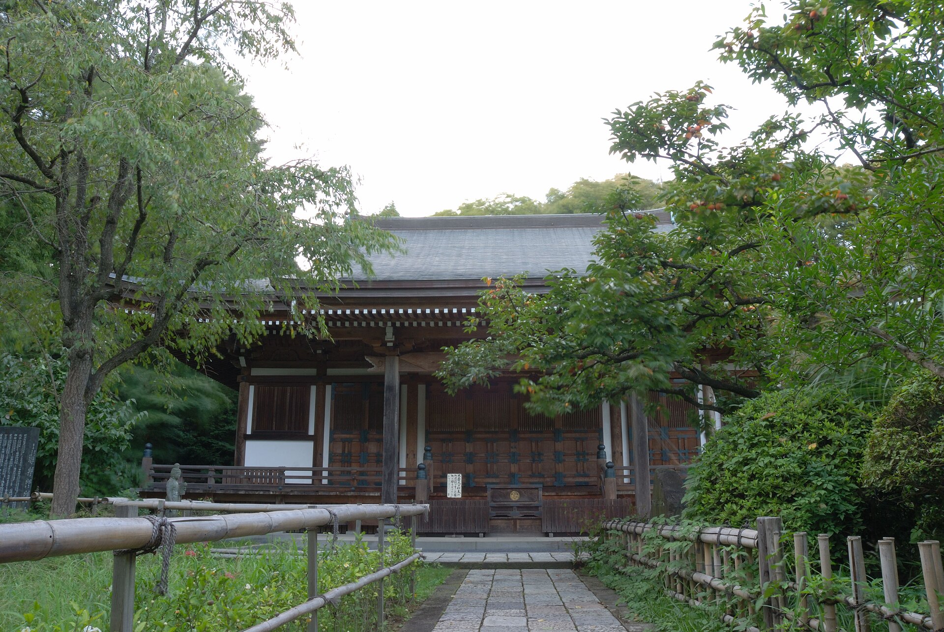 王禅寺の本堂。手前に石畳の道があり、右に実をつけた柿の木が見える